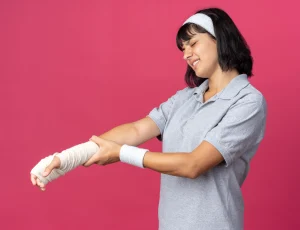 Seorang perempuan tampak memegang tangannya yang mengalami cedera, menggambarkan rasa nyeri dan ketidaknyamanan akibat kemungkinan patah tulang
