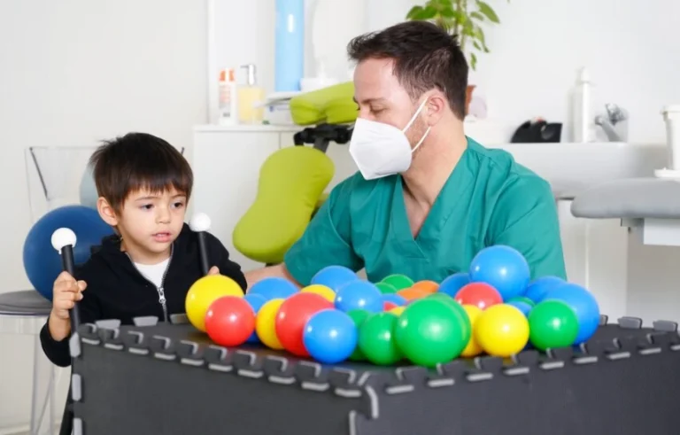 Terapis sedang bermain sambil melakukan terapi dengan seorang anak pasien.